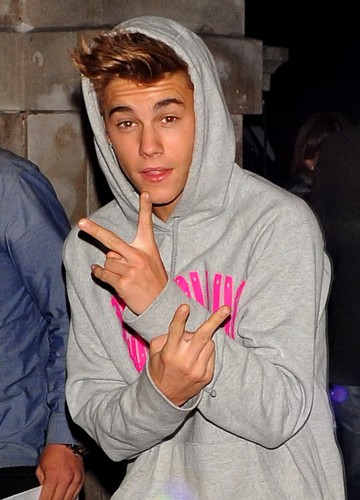Justin Bieber Hotel flashing the peace sign wearing a hoodie